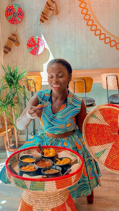 Woman in a dress eats food from a platter in a light and colourful restaurant
