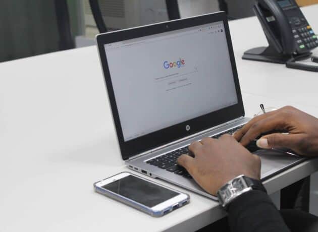 Laptop On A Desk With Google Open. Mobile Phone Next To It