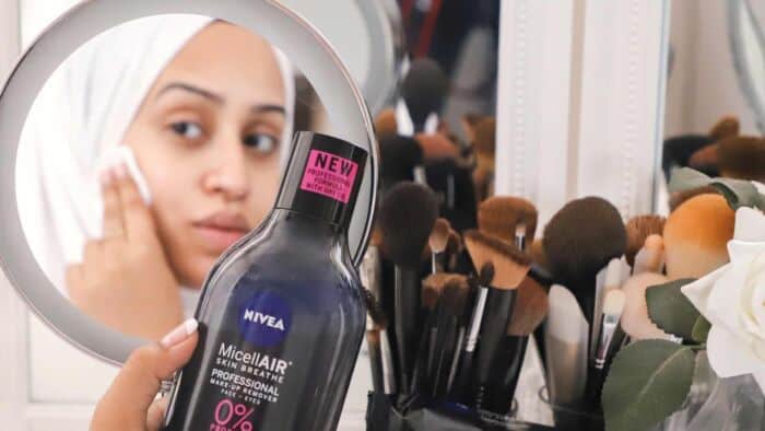 Woman Looking In Mirror Using Beuaty Brands Nivea Micellair On Her Face.