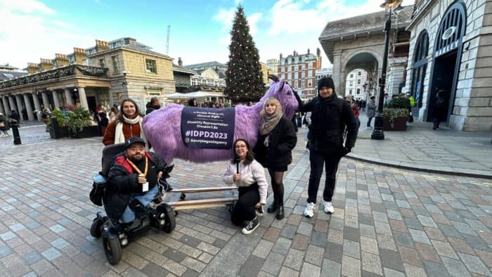 Member Sof The Purple Goat Team Stood Outside With A Giant Fluffy Purple Goat